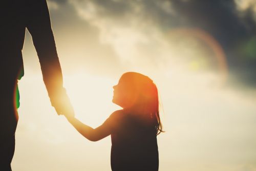 Silhouette of Child Holding Parent's Hand in North Dakota Sunset - Fremstad Law