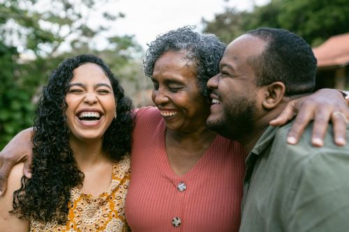 Mother hugging smiling adult children outdoors. - elder care family disputes concept